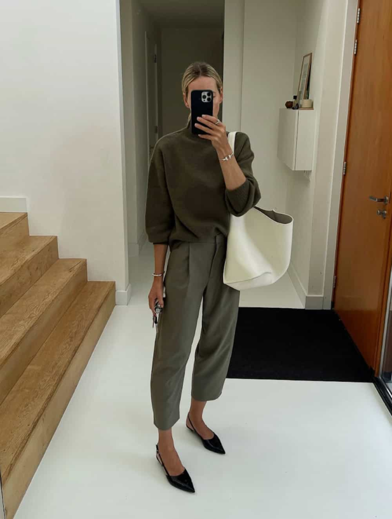 Woman wearing olive green cropped trousers with a matching knit top, styled with pointed-toe flats and minimal silver jewelry.