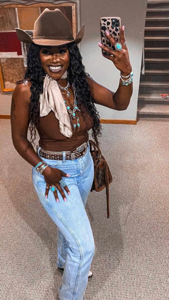 Brown crop top with light wash jeans styled with turquoise jewelry and cowboy hat for a boho baddie cowgirl outfit.