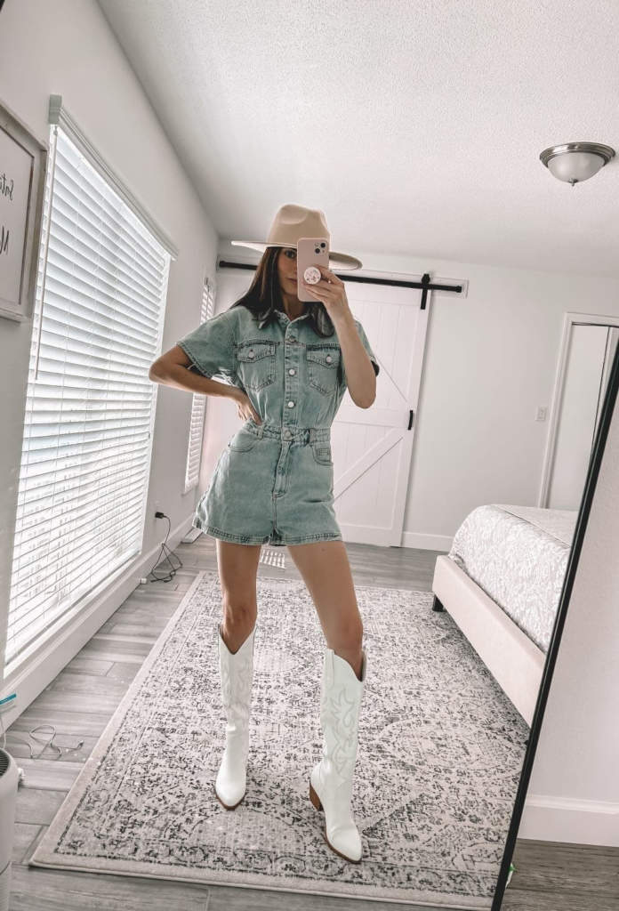 Light wash denim romper styled with white cowboy boots and neutral cowboy hat for a chic baddie cowgirl outfit.
