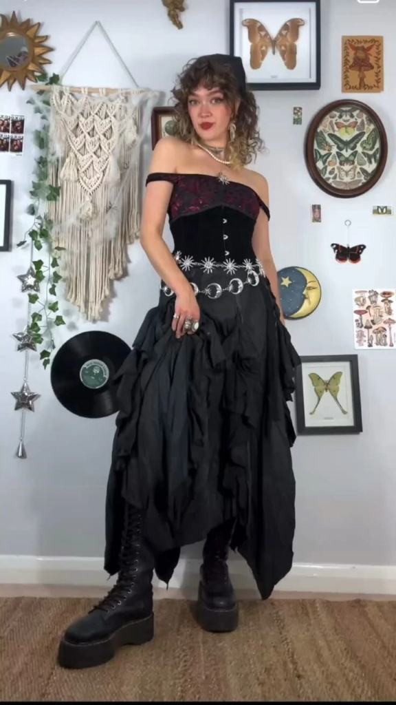 Burgundy velvet corset top paired with an asymmetrical black skirt, celestial moon belt, and chunky platform boots in a boho goth outfit