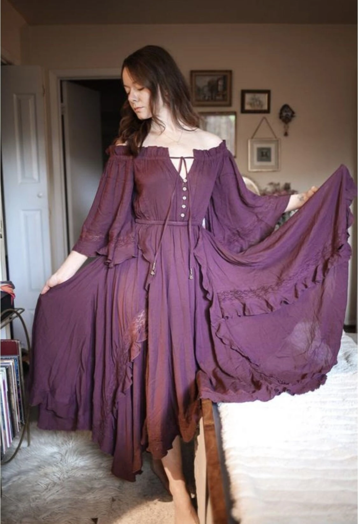Plum-colored off-shoulder boho goth dress with billowing sleeves and layered skirt creating a mystical romantic silhouette