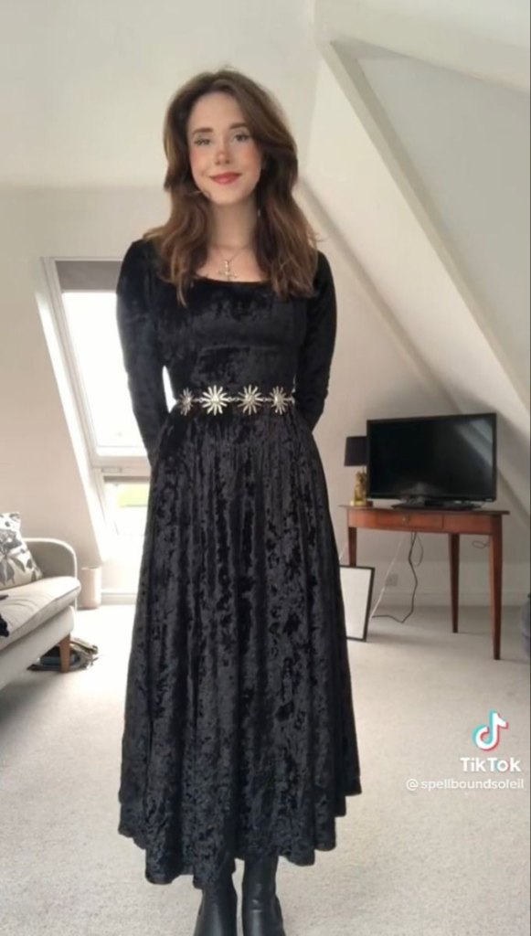 Black long-sleeve velvet dress with star-embellished belt and flowing skirt in a boho goth outfit